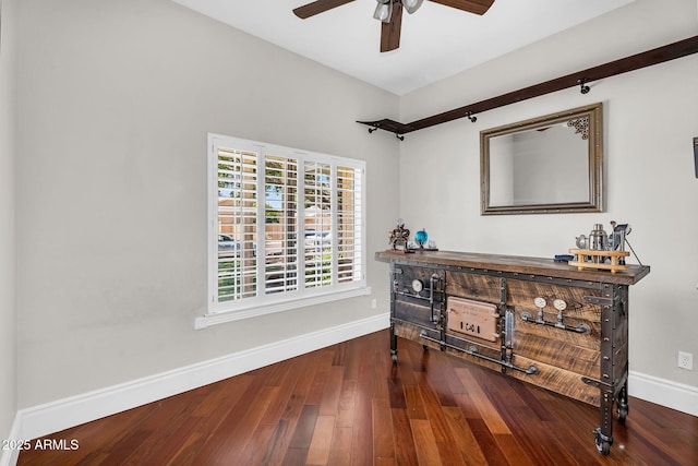 interior space with a ceiling fan, baseboards, and wood finished floors