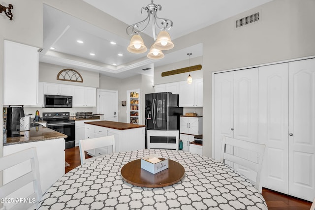 kitchen featuring an inviting chandelier, butcher block countertops, a center island, visible vents, and black appliances
