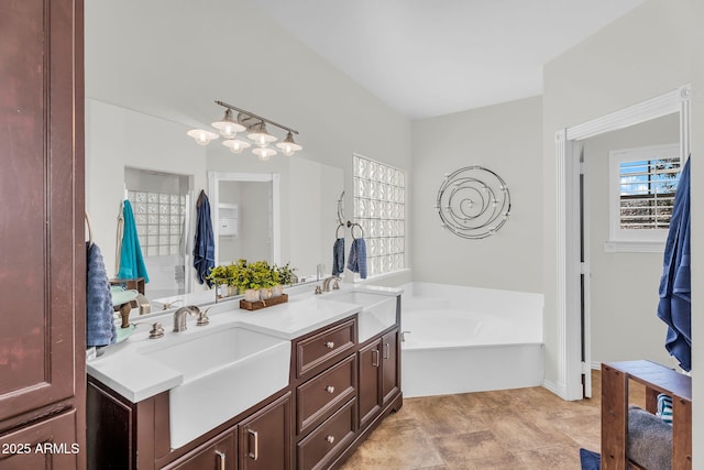bathroom featuring a sink, a garden tub, and double vanity