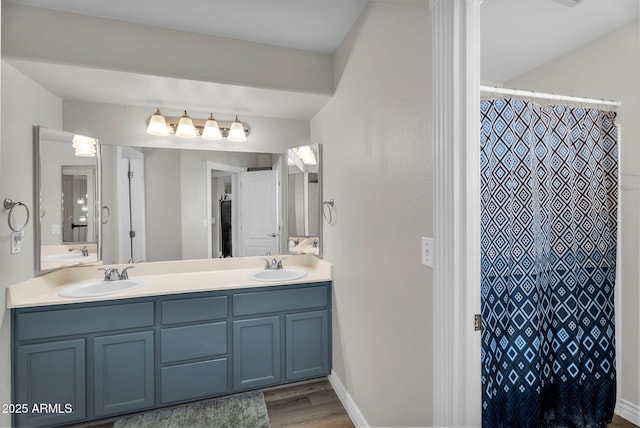 full bath with a shower with shower curtain, double vanity, a sink, and wood finished floors