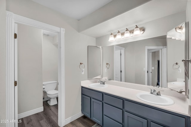 full bath with baseboards, a sink, wood finished floors, and toilet