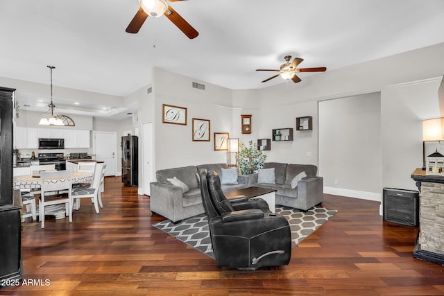living room featuring baseboards, ceiling fan, and dark wood-style floors