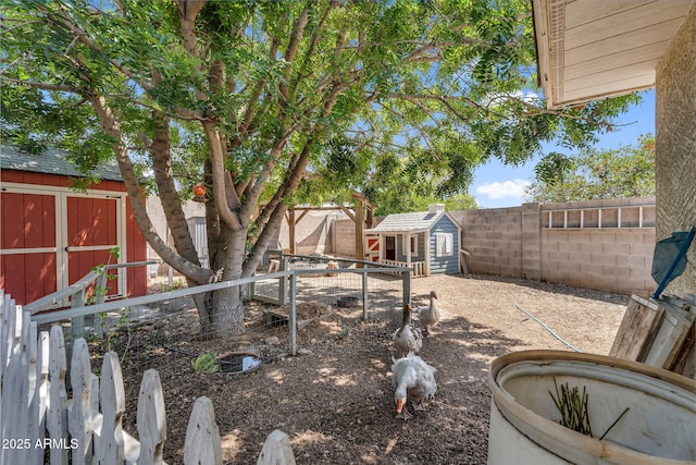 view of yard with a storage shed, an outbuilding, and a fenced backyard