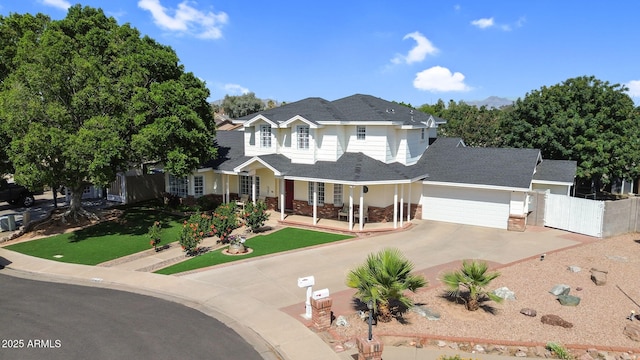 traditional-style house featuring fence, a shingled roof, a garage, concrete driveway, and covered porch
