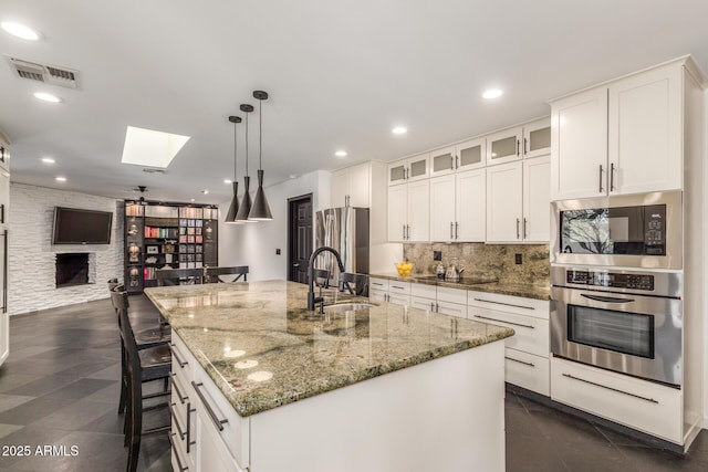 kitchen with stainless steel appliances, a skylight, a sink, visible vents, and tasteful backsplash