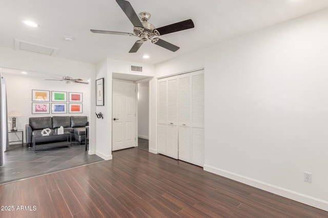 unfurnished bedroom with attic access, baseboards, visible vents, ceiling fan, and wood finished floors