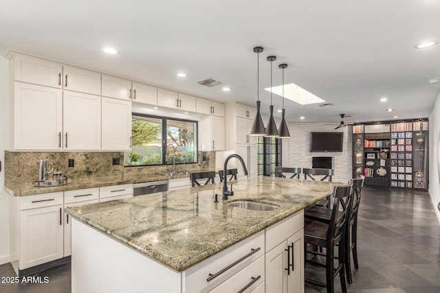 kitchen featuring a breakfast bar, a skylight, a sink, open floor plan, and stainless steel dishwasher