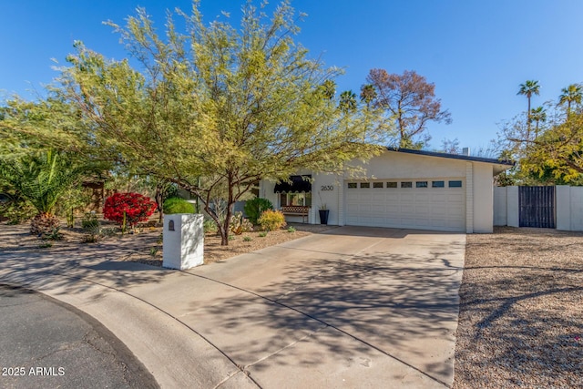 view of front facade featuring stucco siding, driveway, an attached garage, and fence