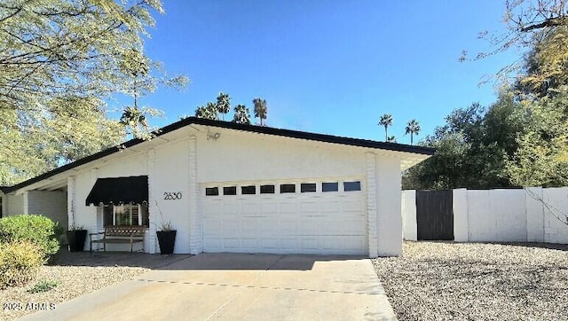 garage featuring concrete driveway and fence