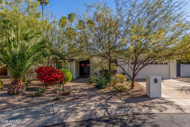 obstructed view of property featuring concrete driveway, an attached garage, and stucco siding