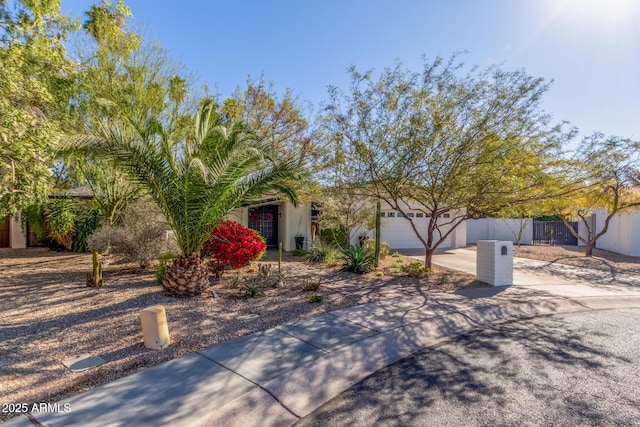 view of front of house featuring a garage, concrete driveway, fence, and stucco siding