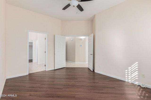 unfurnished bedroom with a closet, a walk in closet, ceiling fan, and dark hardwood / wood-style flooring