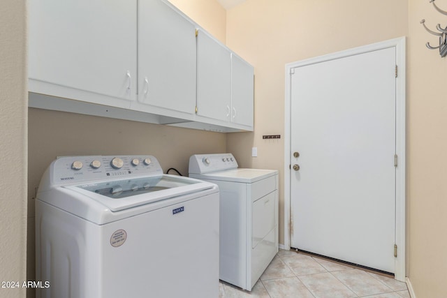 laundry room featuring cabinets, washing machine and dryer, and light tile patterned floors