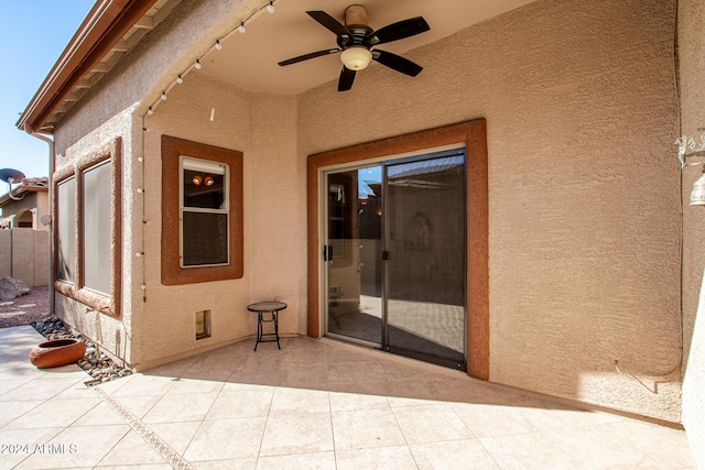 view of exterior entry with ceiling fan and a patio area