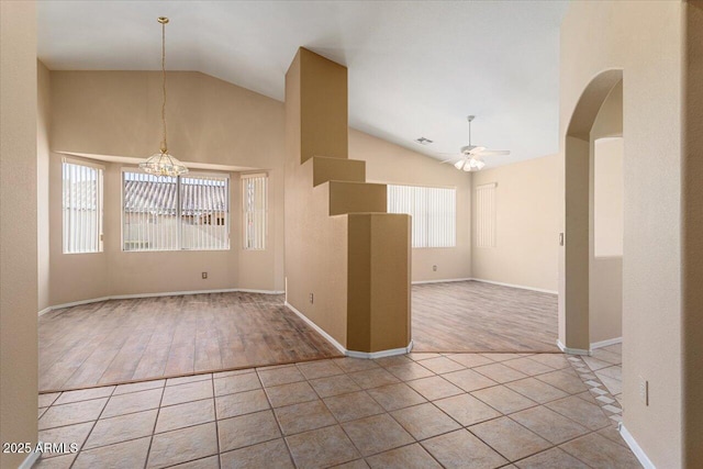 tiled spare room with ceiling fan with notable chandelier and high vaulted ceiling