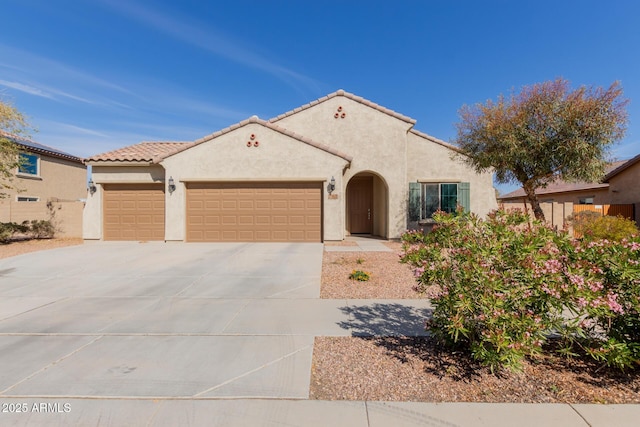 mediterranean / spanish-style home with driveway, a tiled roof, an attached garage, and stucco siding