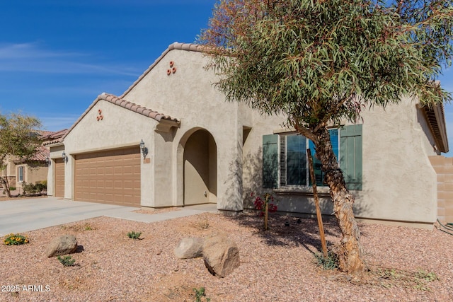 mediterranean / spanish-style home with concrete driveway, an attached garage, a tiled roof, and stucco siding