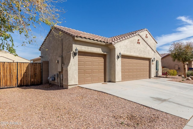 exterior space featuring a garage, fence, a tile roof, driveway, and stucco siding