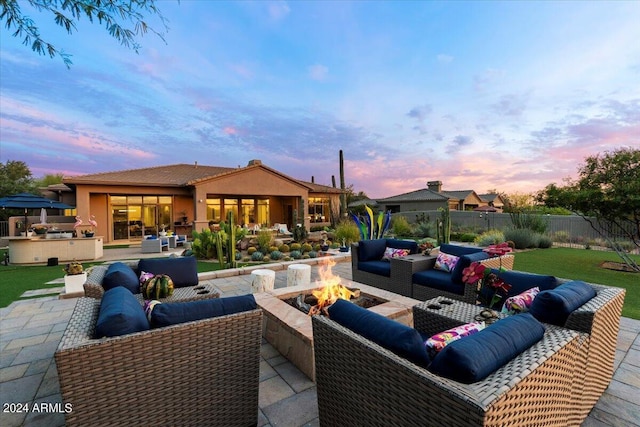 patio terrace at dusk with an outdoor living space with a fire pit