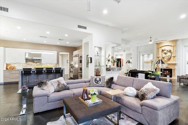 living room with ceiling fan, a large fireplace, and dark tile patterned floors