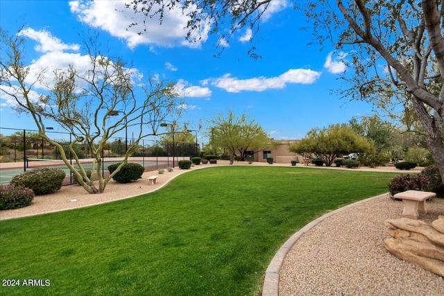 view of home's community featuring a yard and tennis court