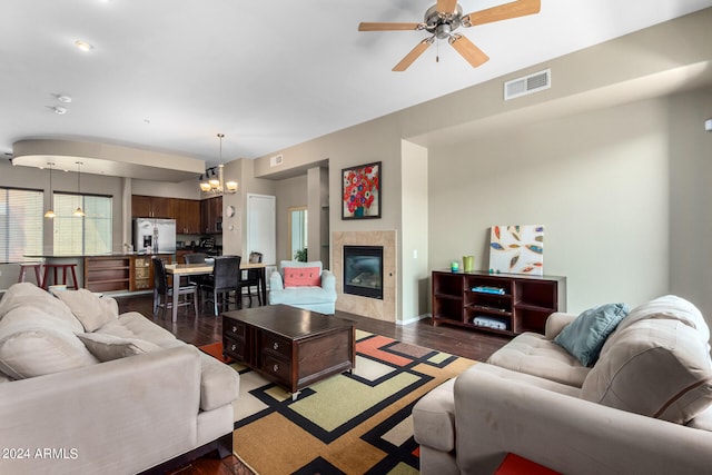 living room featuring ceiling fan with notable chandelier, dark hardwood / wood-style flooring, and a fireplace