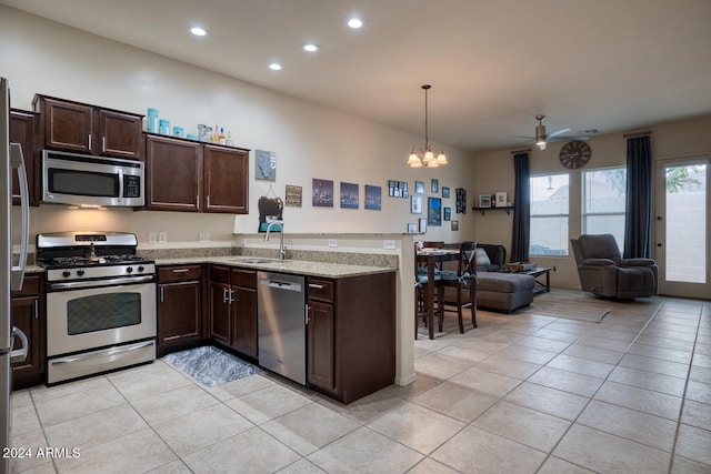 kitchen with sink, decorative light fixtures, light tile patterned flooring, ceiling fan with notable chandelier, and appliances with stainless steel finishes