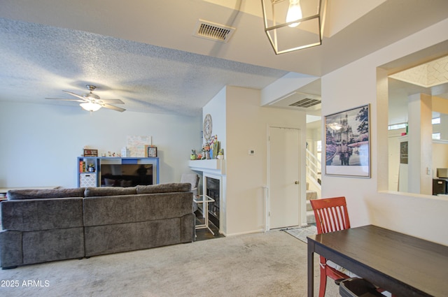 carpeted living room featuring ceiling fan, a textured ceiling, and a fireplace