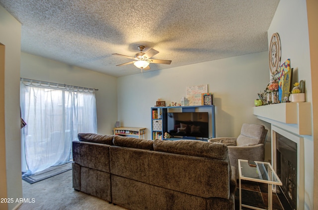 carpeted living room with ceiling fan, a fireplace, and a textured ceiling