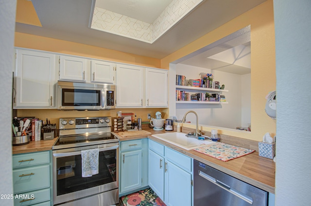 kitchen with stainless steel appliances, sink, white cabinets, and wood counters