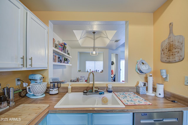 kitchen with dishwasher, sink, pendant lighting, and white cabinets