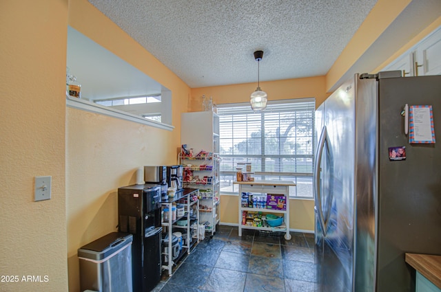 kitchen with white cabinets, a textured ceiling, and stainless steel refrigerator