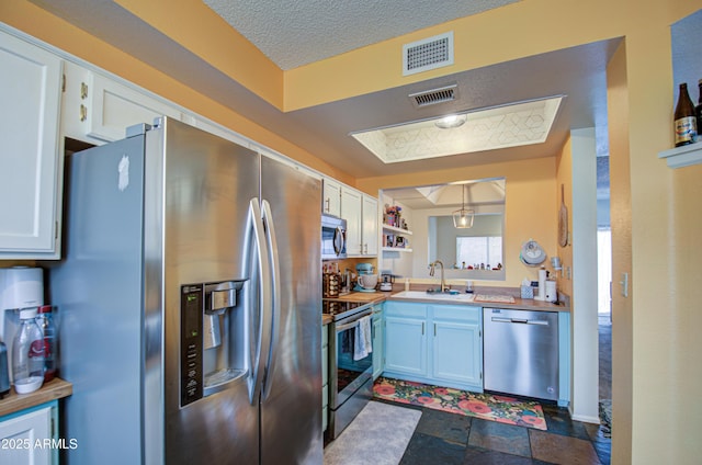 kitchen with pendant lighting, sink, white cabinetry, and appliances with stainless steel finishes