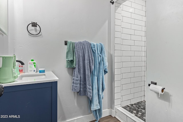 bathroom with a tile shower, vanity, and hardwood / wood-style flooring