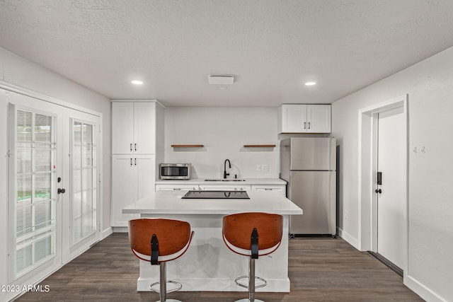 kitchen with dark hardwood / wood-style floors, stainless steel appliances, white cabinetry, and sink