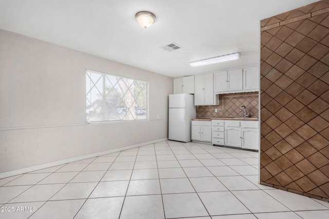 kitchen featuring white cabinetry, white refrigerator, tasteful backsplash, sink, and light tile patterned flooring