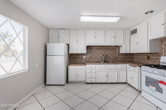 kitchen with sink, white appliances, white cabinets, and a healthy amount of sunlight