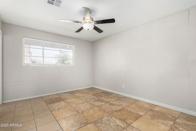 unfurnished room with ceiling fan and brick wall