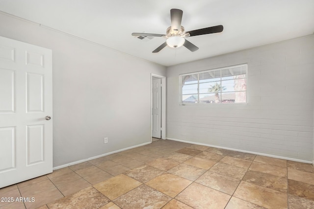 spare room featuring ceiling fan and brick wall