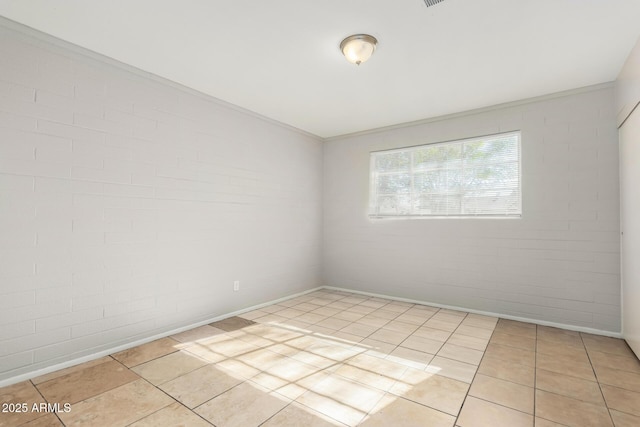 spare room featuring light tile patterned floors, brick wall, and crown molding