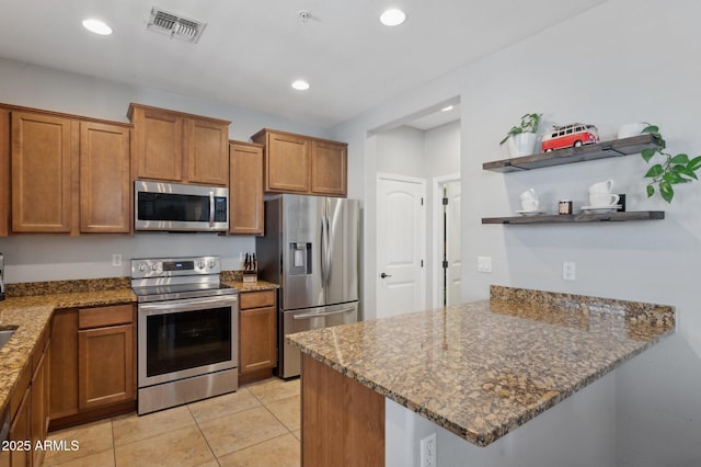 4772 E Portola Valley Dr Unit 102, Gilbert, AZ 85297 - kitchen with appliances with stainless steel finishes, open shelves, a peninsula, brown cabinetry, and stone countertops