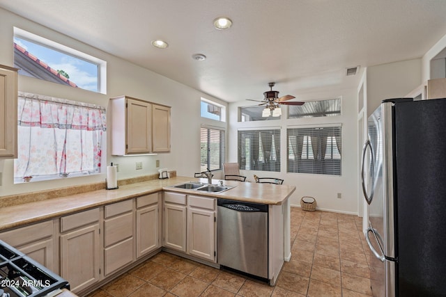 kitchen with appliances with stainless steel finishes, light tile patterned flooring, sink, kitchen peninsula, and ceiling fan