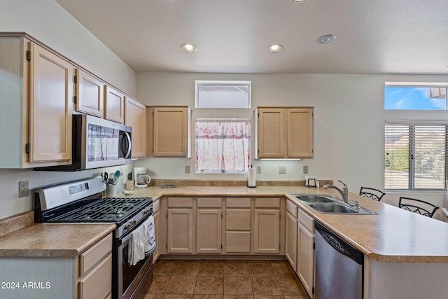 kitchen featuring light brown cabinetry, sink, kitchen peninsula, dark tile patterned floors, and stainless steel appliances