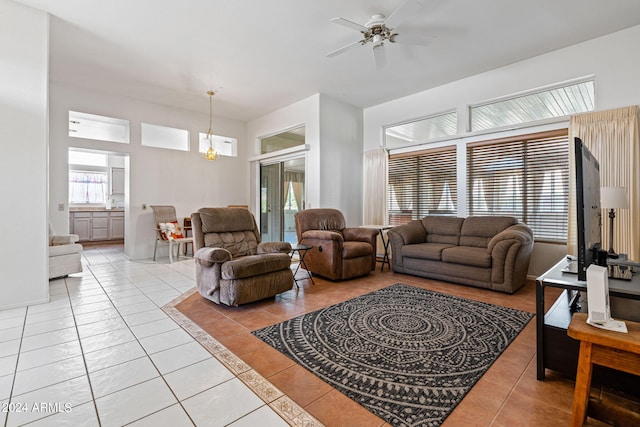 tiled living room featuring ceiling fan with notable chandelier