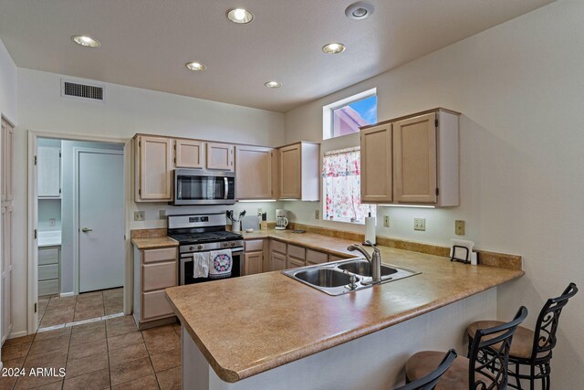 kitchen with sink, light brown cabinets, kitchen peninsula, and stainless steel appliances