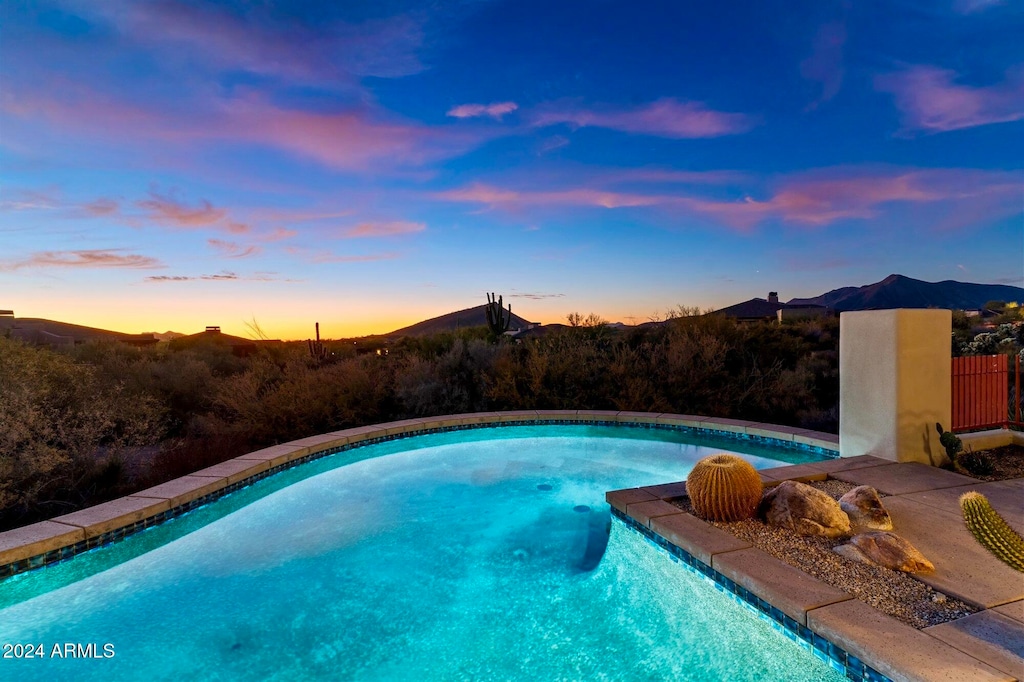 pool at dusk featuring a mountain view