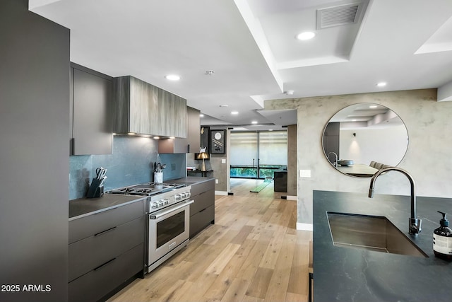 kitchen with visible vents, a sink, high end stainless steel range, modern cabinets, and light wood-type flooring