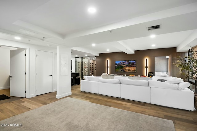 living area with wood finished floors, visible vents, a tray ceiling, recessed lighting, and beamed ceiling