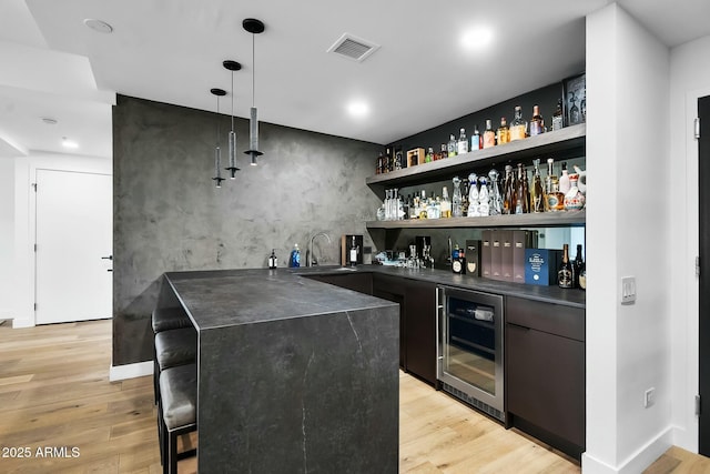 bar featuring indoor wet bar, wine cooler, visible vents, and light wood-style flooring