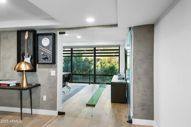 interior space with a raised ceiling, wood finished floors, baseboards, and expansive windows